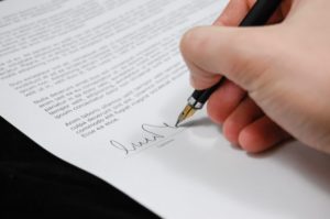 A hand signs a legal document